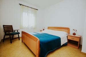 a bedroom with a bed and a chair and a window at Apartments Doulos in Splitska