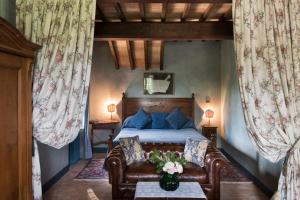 een slaapkamer met een bed, een bank en gordijnen bij Tenuta Di Canonica in Todi