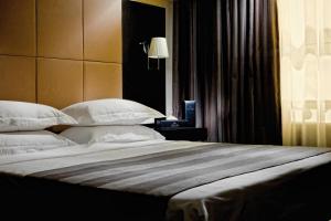 a large bed with white pillows in a bedroom at Voyage Hotel in Karagandy +33 photos