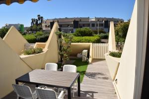 een patio met een tafel en stoelen op een balkon bij HELIOPOLIS CAP D'AGDE VILLAGE NATURISTE in Cap d'Agde