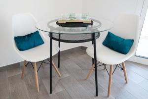 een glazen tafel en twee stoelen met blauwe kussens bij Apart EAM Maite 3 in Benalmádena +11 foto's