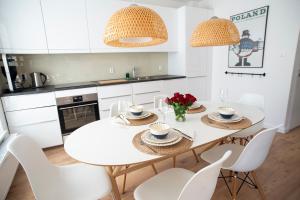 een witte keuken met een witte tafel en stoelen bij 365PAM - Marina i Dom Rodzinny - BASEN ZEWNĘTRZNY, KORT TENISOWY, SIŁOWNIA, PLAC ZABAW, BOISKO in Ustronie Morskie