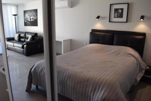een slaapkamer met een bed en een zwarte bank bij HELIOPOLIS CAP D'AGDE VILLAGE NATURISTE in Cap d'Agde