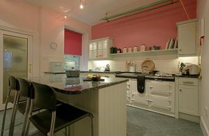 una cucina con pareti rosse e bancone con sedie di Netherwood House a Newtonmore