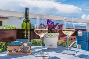 two glasses of wine on a table with a bottle of wine at Guest House Djurdjica in Dramalj
