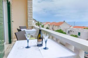 a bottle of wine and two glasses on a balcony at Apartments and Room Napoli in Bol