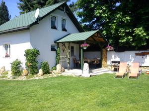 a white house with chairs and a table in the yard at Chata Bešeňová in Bešeňová