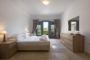 a bedroom with a bed and a dresser and a window at Villa Emerald in Porto Heli
