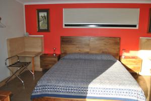 a bedroom with a bed and a red wall at Wompoo Eco Retreat in Cow Bay