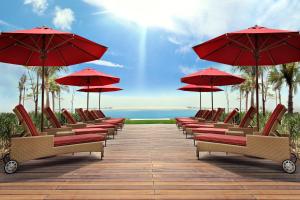 a row of chairs with red umbrellas on a boardwalk at Khalidiya Palace Rayhaan by Rotana, Abu Dhabi in Abu Dhabi