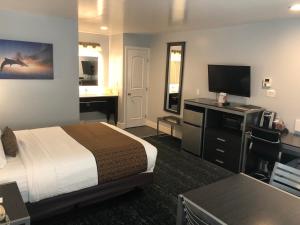 a hotel room with a bed and a desk with a television at Pacific Inn Monterey in Monterey