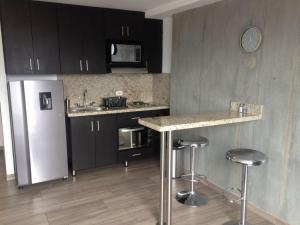 a kitchen with a refrigerator and a counter with stools at All Inclusive Suites in Medellín