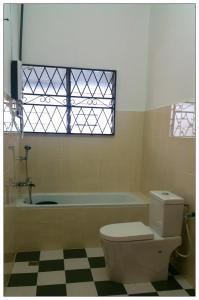 a bathroom with a toilet and a tub and a window at GuestHouse Taman Megah, Lot 19 in Sandakan