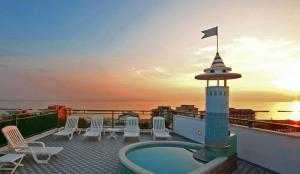 una terraza en la azotea con bañera de hidromasaje y sillas en Hotel Wivien, en Cesenatico