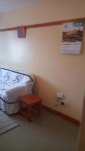 um pequeno quarto com uma cama e um banco vermelho em Ash house 2 em Nairobi