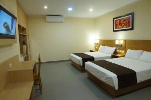 a hotel room with two beds and a flat screen tv at Águila Dorada Selva Hotel in Pucallpa