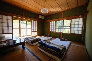 two beds sitting in a room with windows at YOKI Guest House in Miyoshi