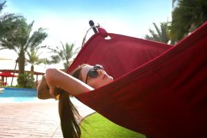 a woman laying in a hammock near a pool at Khalidiya Palace Rayhaan by Rotana, Abu Dhabi in Abu Dhabi