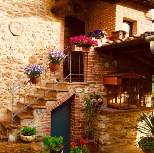 a brick building with flower pots and a blue door at Molino dei Preti in Asciano