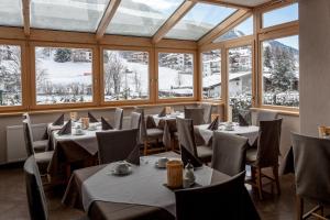 a dining room with tables and chairs and windows at Hotel Garni Villa Park in Ortisei