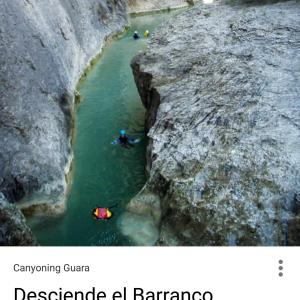 un groupe de personnes faisant du rafting dans une rivière entre deux rochers dans l'établissement Carmen De Arnas, à Colungo