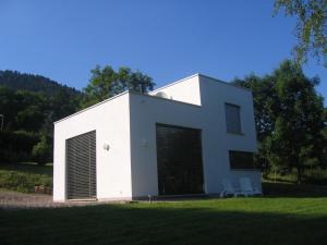 a white house with two chairs in the grass at Le Cube in Nayemont-les-Fosses