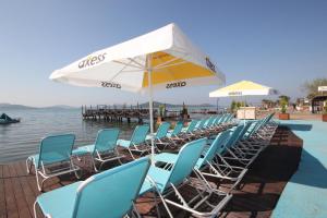 a row of chairs and umbrellas next to the water at Ezer Hotel in Ayvalık