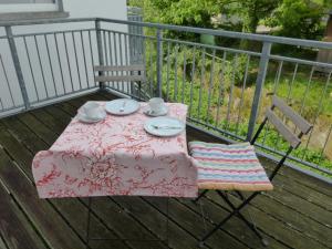 バート・ケーニヒにあるFerienwohnung an der Kimbach 2のテーブルと椅子、テーブル、皿、カップが備わるデッキです。