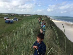 a group of children walking up a hill near the beach at Løkken Strand Camping in Løkken +7 photos