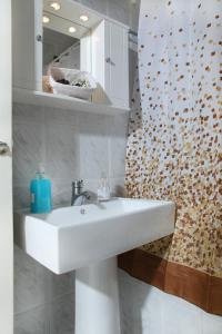een badkamer met een witte wastafel en een spiegel bij Alexandra in Kineta