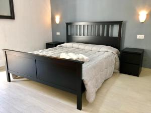 una camera da letto con un grande letto nero con due comodini di Blue House a Cefalù