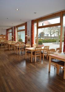 ein Restaurant mit Holztischen, Stühlen und Fenstern in der Unterkunft Klostergasthof Roggenburg in Roggenburg
