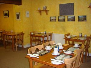 The Anchorage Guest House في واتيرفورد: غرفة طعام مع طاولات وكراسي خشبية