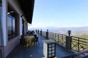 a balcony with tables and chairs and a view of the mountains at Woodsvilla Residency in Rānīkhet