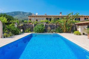 a blue swimming pool in front of a house at Finca - Agroturisme Sa Parellada in Binibona