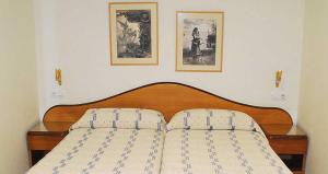 a bed in a bedroom with two pictures on the wall at Hostal La Barretina in Figueres