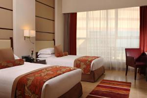 a hotel room with two beds and a desk at Khalidiya Palace Rayhaan by Rotana, Abu Dhabi in Abu Dhabi