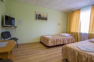 a room with two beds and a desk and a tv at Gostinica Garmnonia Plus in Velikiye Luki