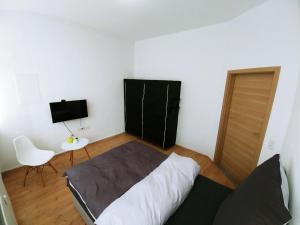 a bedroom with a bed and a chair and a television at Pension BeOne in Trossingen