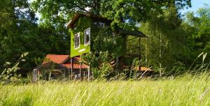 une cabane dans les arbres au milieu d'un champ dans l'établissement Tree house Ramona & Fairytale wooden house by Ljubljana, à Grosuplje