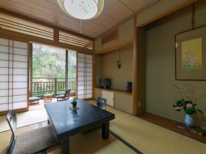 a room with a table and a large window at Ryori Ryokan Shikanoyu in Ena