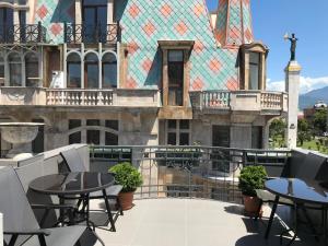 een balkon met tafels en stoelen voor een gebouw bij Guest House On Europe Square in Batoemi