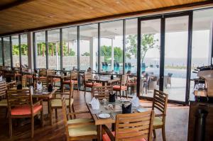 a restaurant with wooden tables and chairs and a pool at Regenta Arie Lagoon Negombo in Negombo