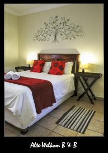 a bedroom with a large bed with red pillows at Alte Welkom Guesthouse in Klerksdorp