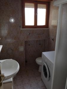 bagno con lavandino e servizi igienici e lavatrice. di Villa Pellarini a Lignano Sabbiadoro
