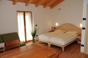 a bedroom with a bed and a green chair at Agritur alla Veduta in Trento