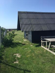 a picnic table next to a building with a bench at Løkken Strand Camping in Løkken