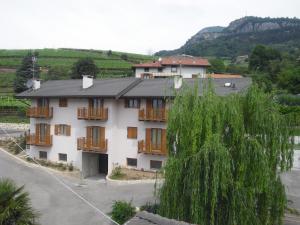 a large white building with wooden balconies and a tree at Agritur alla Veduta in Trento