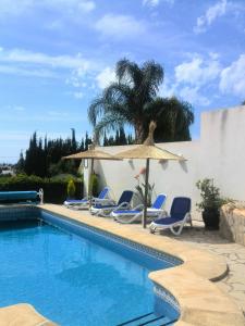 einen Pool mit Stühlen und einem Sonnenschirm in der Unterkunft Villa ARMONIA in Benissa