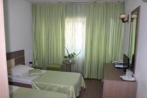 a bedroom with two beds and a window with green curtains at Hotel Ciucas in Vălenii de Munte